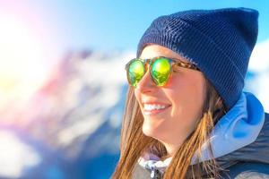 skieuse avec des skis souriant et portant des lunettes de ski photo