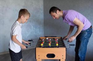 mignonne garçon en jouant table Football avec le sien émotif papa dans le pièce photo