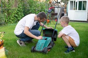 papa et le sien curieuse fils tondre le pelouse. démonter le pelouse tondeuse photo