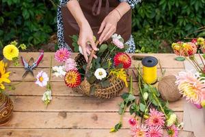 le fleuriste fait du une bouquet dans une panier de l'automne coloré bourgeons photo