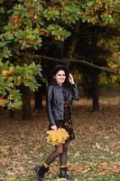 une fille dans une noir chapeau détient Jaune l'automne feuilles dans sa mains photo