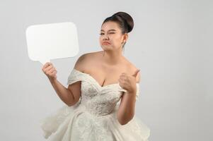 jeune belle mariée asiatique pose avec une maquette de bannière à la main photo