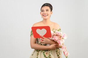 belle mariée asiatique souriante et posant avec signe de coeur sur fond blanc photo