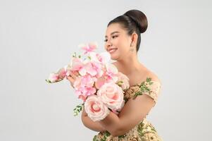 Jeune belle mariée asiatique avec bouquet d'orchidées sur fond blanc photo