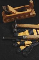 ensemble d'outils pour charpentiers, marteau, ciseau et avion avec fond en bois foncé gants. photo