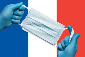 médecin en portant respiratoire visage masque dans mains dans bleu gants sur Contexte drapeau de drapeau de France ou français tricolore. concept coronavirus quarantaine, pandémie déclenchement photo