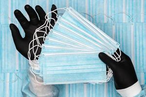 médecin en portant lot bleu chirurgical médical visage masques dans noir protecteur gant dans mains photo