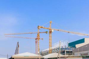 Grues de construction industrielle et bâtiment dans un beau fond de ciel bleu photo