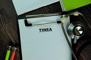 Tinea écrit sur paperasse isolé sur table en bois photo