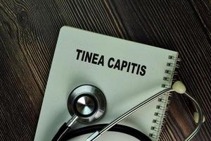 Tinea capitis écrit dans un livre isolé sur table en bois photo