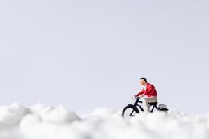 voyageurs miniatures à bicyclette dans la neige, concept de fond d'hiver photo