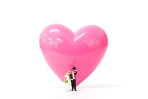 Couple miniature avec un coeur rose sur fond blanc, concept de la Saint-Valentin photo