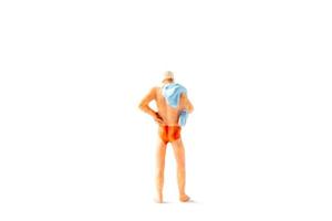 Personne miniature portant un maillot de bain debout sur un fond blanc, concept de l'été photo