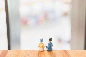 Couple miniature assis sur un pont en bois photo