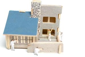 Peintres miniatures peignant une maison en bois sur fond blanc photo