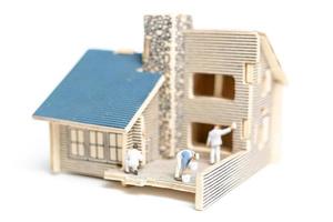 Peintres miniatures peignant une maison en bois sur fond blanc photo