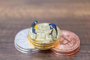 Travailleurs miniatures faisant de la crypto-monnaie bitcoin sur un fond de bois photo