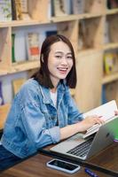 Jeune asiatique fille en train d'étudier à bibliothèque photo