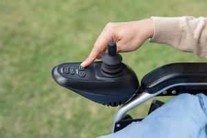 asiatique femme patient sur électrique fauteuil roulant avec manette contrôle à hôpital. photo