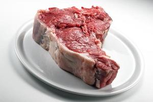 Bifteck d'os cru sur une assiette ronde blanche photo