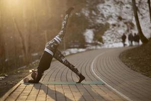 Une jeune femme athlétique effectue des exercices de yoga et de méditation à l'extérieur photo