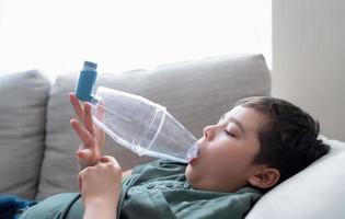 malade enfant en utilisant asthme inhalateur pour allergiques, pauvres garçon fatigué de poitrine tousser en portant inhalateur entretoise, essayé enfant ayant asthme allergie photo