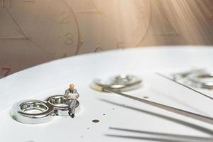 homme d & # 39; affaires miniature assis sur une horloge, concept de temps et de travail photo