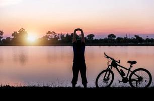 silhouette femme exercice près vélo sur le coucher du soleil photo