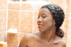 belle femme africaine souriante avec de la crème sur son visage photo