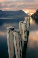 en bois des postes en hausse en dehors de le Lac à spectaculaire le coucher du soleil photo