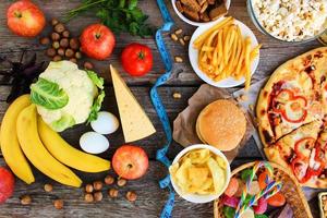 Fast food et en bonne santé nourriture sur vieux en bois Contexte. concept choisir correct nutrition ou de déchet alimentaire. Haut voir. photo