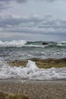 éclaboussure de mer mousse sur le rive de le noir mer. proche en haut mer l'eau vagues avec bulles sur le le sable plage photo