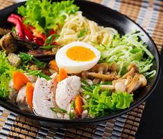Japonais ramen soupe avec poulet, œuf, Shimeji champignons et aubergines sur foncé en bois Contexte. chanko non, sumo soupe. photo
