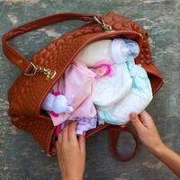 de la mère Sac à main avec articles à se soucier pour enfant sur vieux en bois Contexte. aux femmes mains prendre des choses en dehors de sac. photo