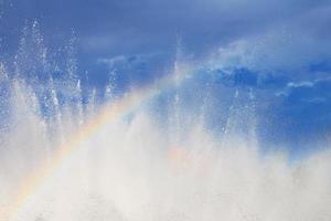 Fontaine avec une arc en ciel contre le bleu ciel photo