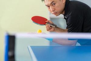 Homme jouant au tennis de table avec raquette et balle dans une salle de sport photo