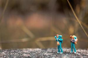 Backpackers miniatures debout sur un sol en béton avec un fond de nature bokeh photo