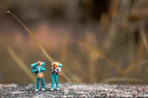Backpackers miniatures debout sur un sol en béton avec un fond de nature bokeh photo