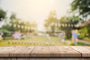 dessus de table en bois vide et bokeh léger flou abstrait et arrière-plan flou d'arbres de jardin au soleil. modèle d'affichage de produit avec espace de copie. photo