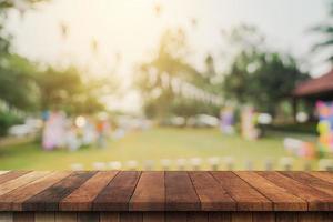 dessus de table en bois vide et bokeh léger flou abstrait et arrière-plan flou d'arbres de jardin au soleil. modèle d'affichage de produit avec espace de copie. photo