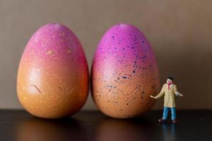 Artiste miniature tenant un pinceau et peignant des oeufs de Pâques pour Pâques photo