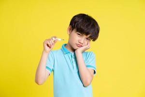 portrait de un asiatique garçon posant sur une Jaune Contexte photo