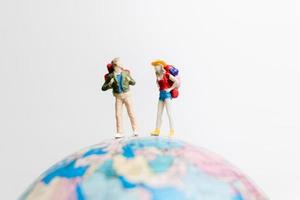 personnes miniatures debout sur un globe avec un fond blanc, concept de voyage photo