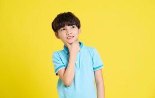 portrait de un asiatique garçon posant sur une Jaune Contexte photo