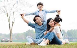 image de un asiatique famille séance ensemble sur le herbe à le parc photo