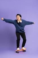 image de Jeune asiatique homme en jouant planche à roulette sur violet Contexte photo