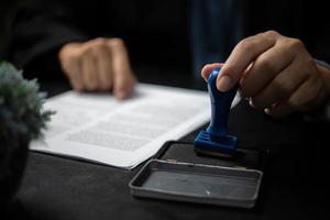 homme tamponnant l'approbation des documents bancaires de financement du travail ou de marketing d'investissement sur le bureau. photo