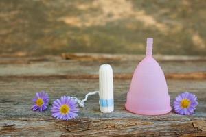 menstruel tasse et tampons sur vieux en bois Contexte. photo