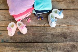 bébé chaussures, Vêtements et sucettes rose et bleu sur le vieux en bois Contexte. Haut voir. plat poser. photo