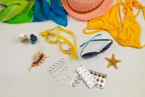 été aux femmes plage accessoires pour votre mer vacances et pilule sur blanc Contexte. concept de des médicaments obligatoire dans voyage. Haut voir. photo